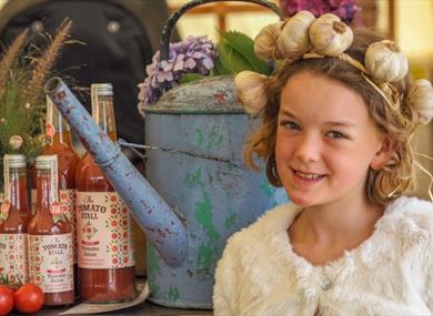 Girl with a garlic head band on standing next to local produce at the Isle of Wight Garlic Festival, what's on, event, Newchurch
