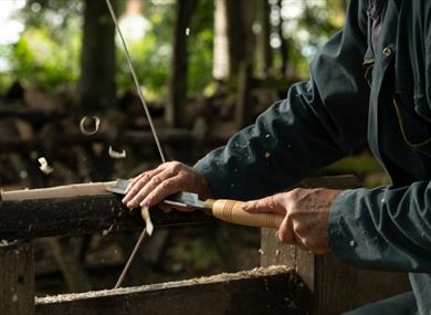 craftsman using chisel on turning piece of wooden leg