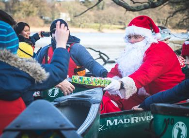 Santa giving a child a present in a canoe