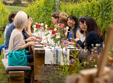 People sat around a table in the vineyard eating