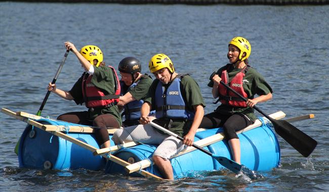 Team Activity Group - 4 adults on a raft made of barrels and wooden battens
