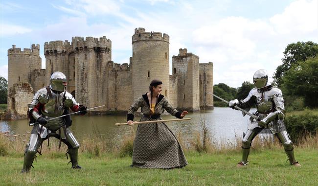 Three people in fighting stances with a castle in the background.