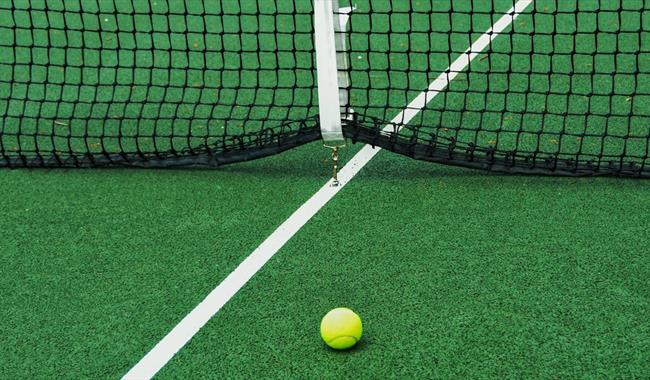 Yellow ball on green tennis court