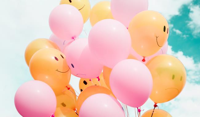 Yellow and pink balloons against a blue sky
