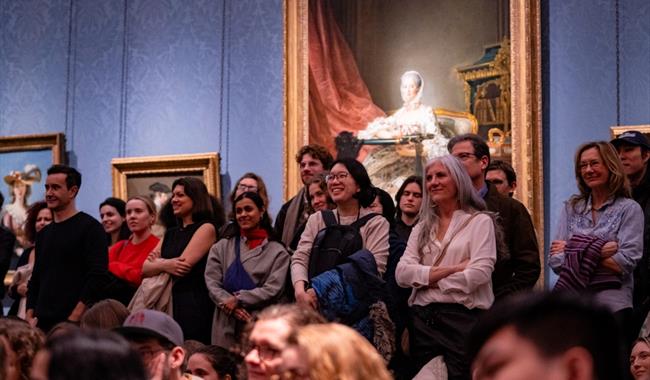 Audience of various people laughing during a comedy night at an art gallery
