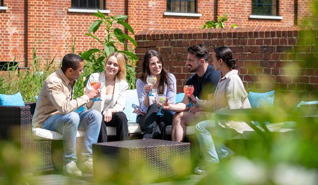 Group of friends gathered at Bombay Sapphire Distillery for Aperitivo Evenings - sitting outside by the River Test