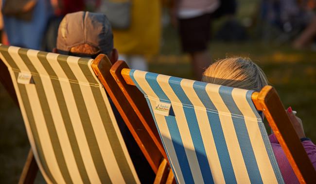 Two people sat in a deckchair at a summer event