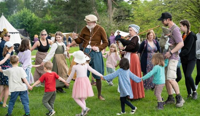 visitors dancing in a circle around a tudor reenactor