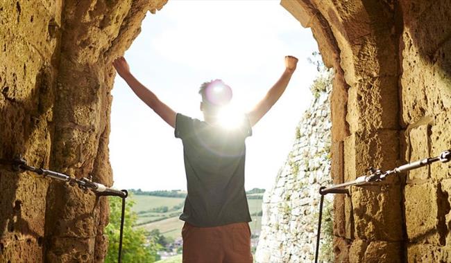 Man standing in arch of Carisbrooke Castle looking at the view, historic attraction, family fun, children's activities, summer event, what's on, Isle