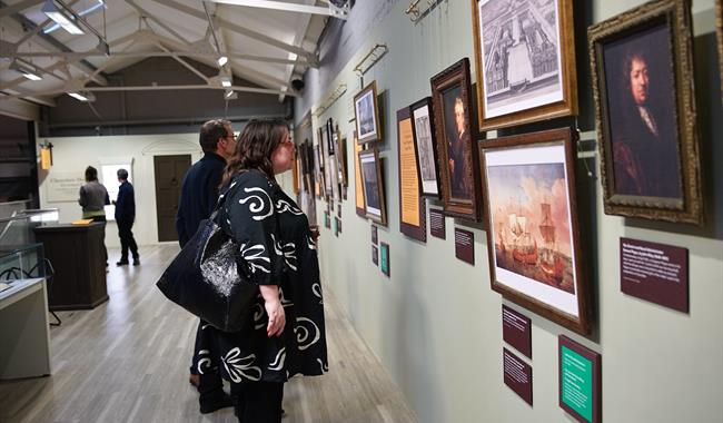 A woman looking at a range of framed photographs inside an exhibition space.