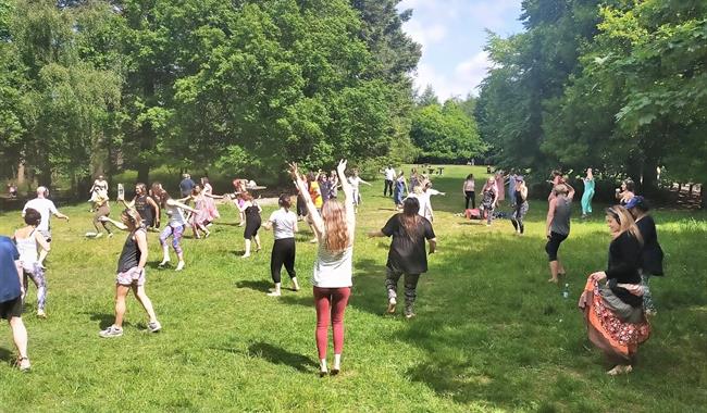 A group dancing barefoot among trees