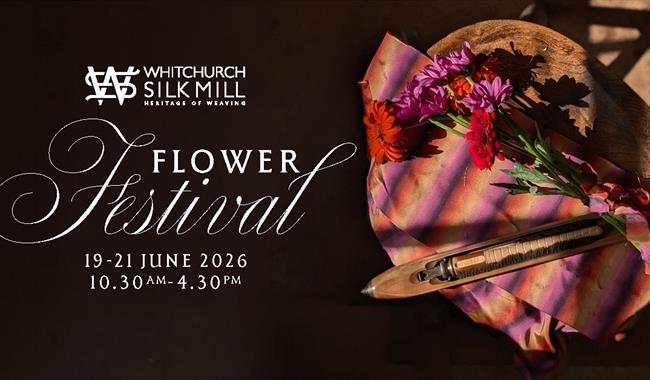 Black background with small bouquet laid on top of  with brightly coloured striped fabric in pinks & oranges.