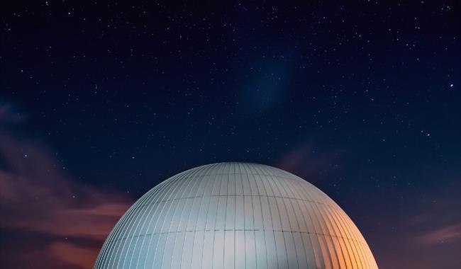 A domed planetarium beneath a clear, star-filled night sky