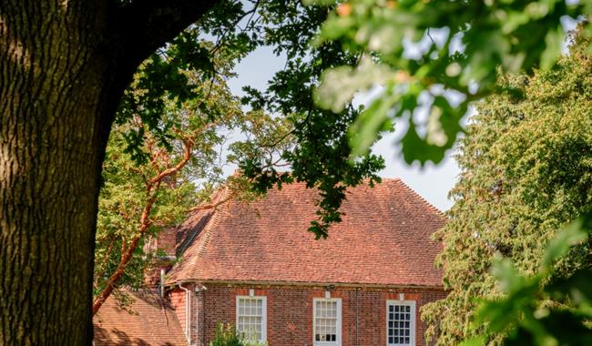 Colour photograph showing a traditional house in the Sussex countryside