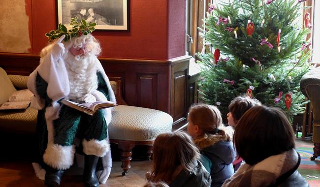 Father Christmas talking to a group of children by a Christmas tree