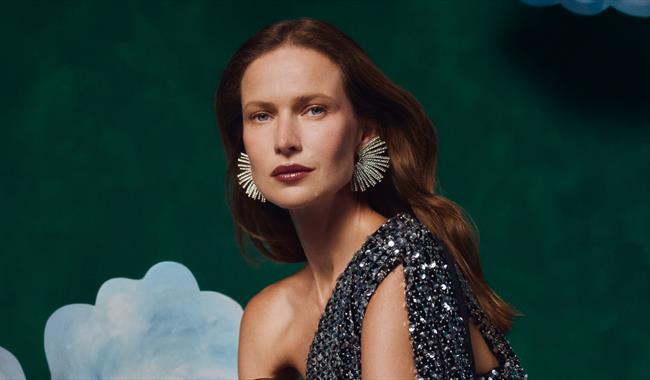 Woman wearing an evening dress behind a painted green background with white clouds