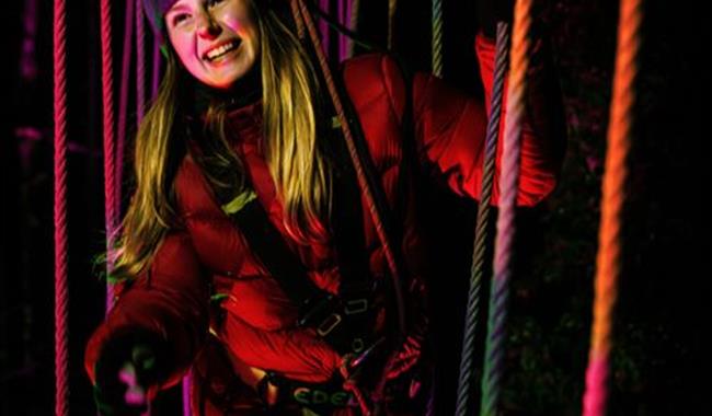 Lady up in the trees for Go Ape after dark experience, for adults only at Tilgate Park in Crawley, Sussex