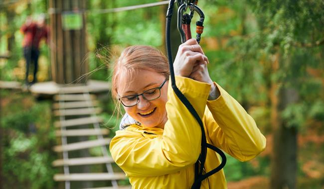 Girl clipped on having fun at Go Ape Southampton at Itchen Valley Country Park, Hampshire