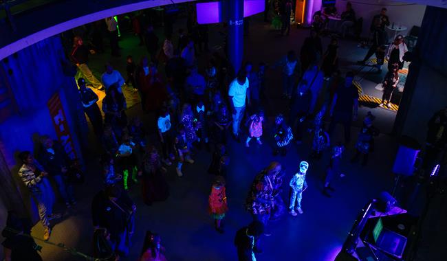 Halloween disco with lots of children and adults in luminous outfits