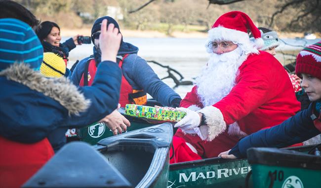 Santa giving a child a present in a canoe