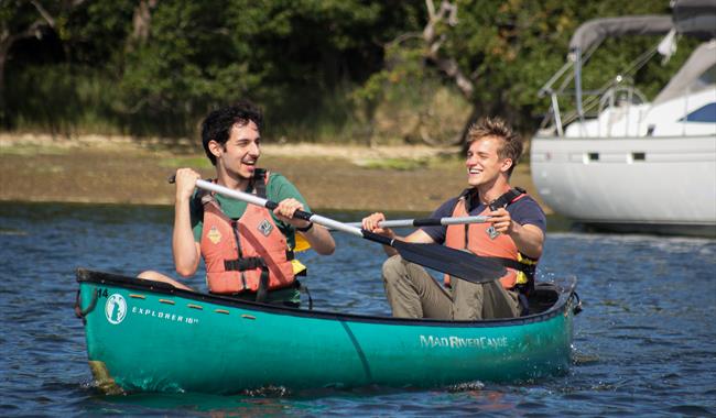 Two people splashing about on the water on a canoe.