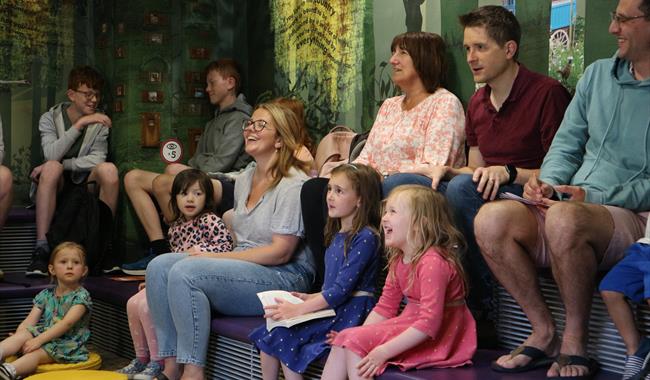 A group of families watching a storytelling session. A close-up of their faces laughing