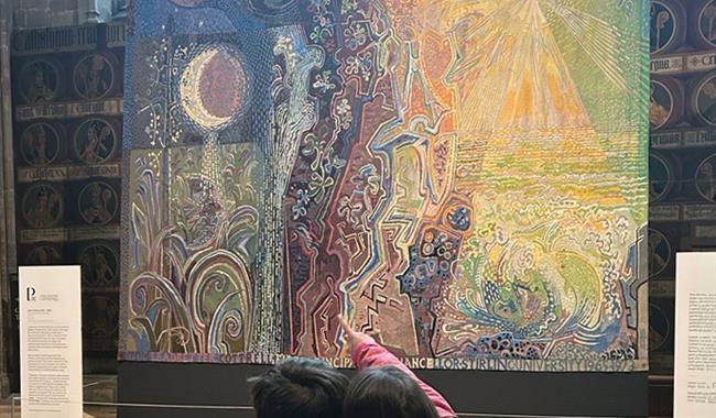 2 children looking at a large tapestry