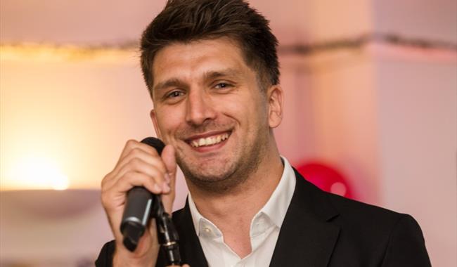 a man smiling while holding a microphone