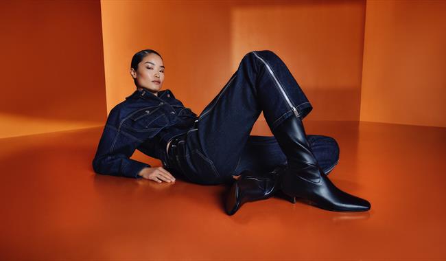 Female model dressed in denim surrounded by an orange backdrop