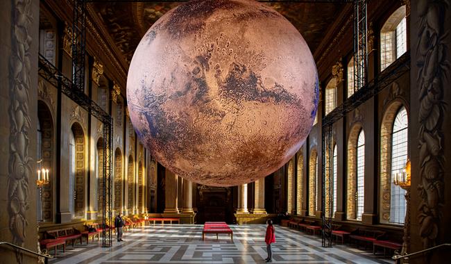 A large, realistic rendering of the planet Mars is suspended in the center of the Painted Hall. The Mars exhibit is spherical and measures seven meter
