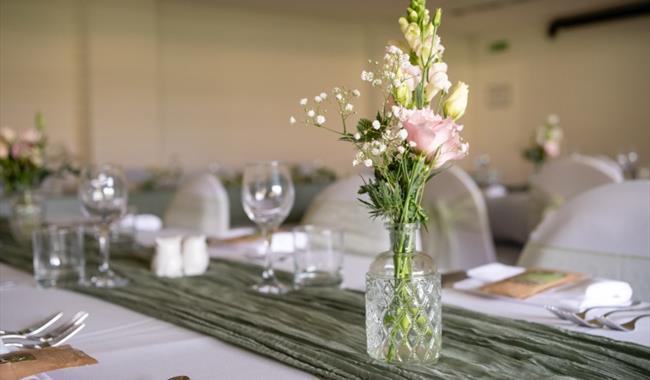 A vase of pink roses sat on a neatly set table