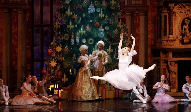 Ballet dancer performing in The Nutcracker in front of a large Christmas tree