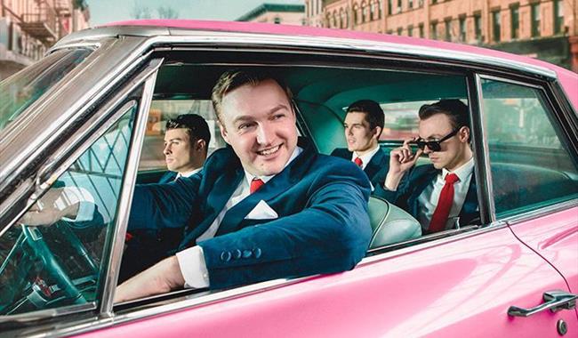 4 people wearing suits in a car