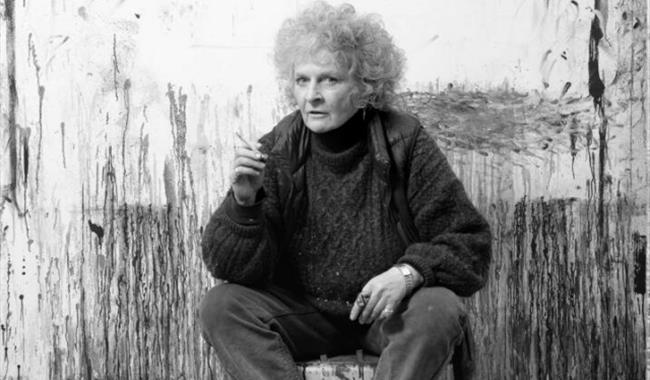 Maggi Hambling seated in front of her artwork