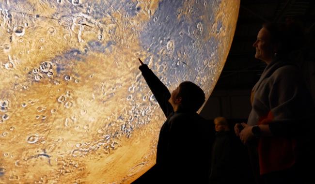 A child points at Mars