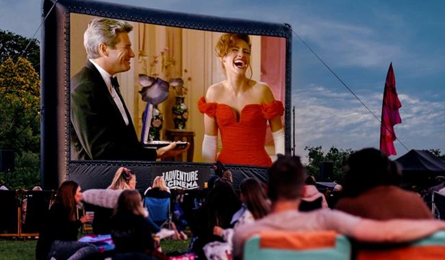 Visitors enjoy outdoor cinema seated on camping chairs.