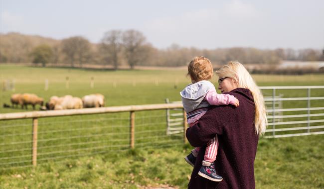mother and daughter standing in front of sheep field