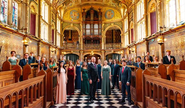 The Choir of Royal Holloway standing in their gilded Chapel.