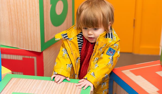 A boy playing with giant letter blocks