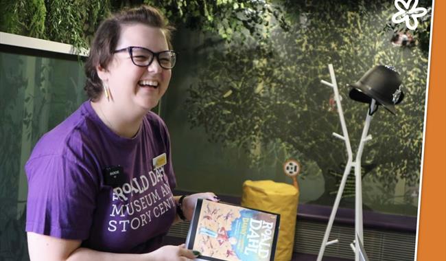 Woman in a purple t-shirt smiling and holding a book
