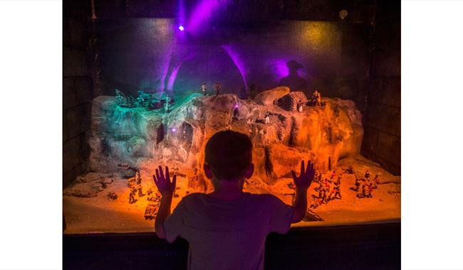 Child looking at a miniature model of smugglers using the caves, at Smugglers adventure Hastings