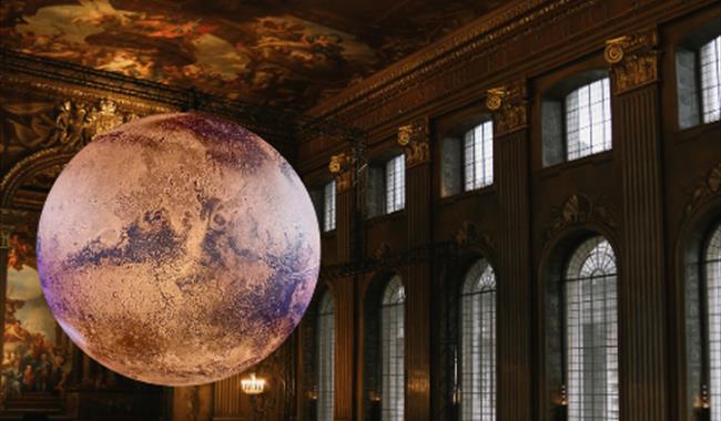 In a grand, ornate hall with a high, frescoed ceilings (the Painted Hall), a large, glowing model of planet Mars is suspended in the centre of the roo