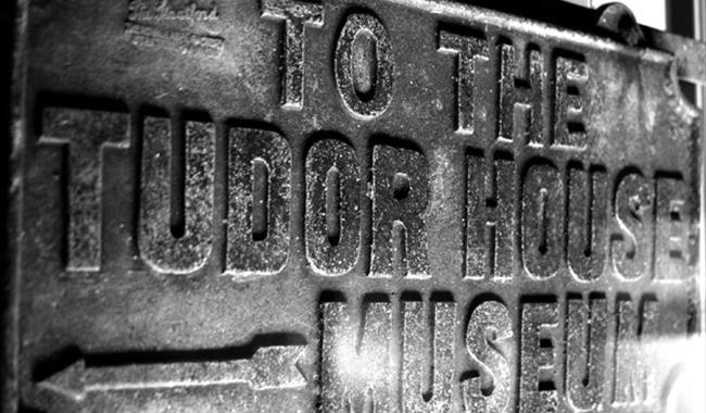 Spooky black and white photo of and old Tudor House Museum sign