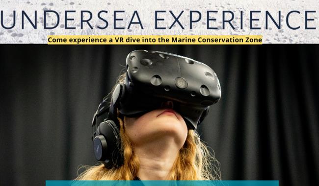 A photograph of a girl with long blonde hair wearing a virtual reality headset. The text above her says "The Living Coast Undersea Experience. Come ex