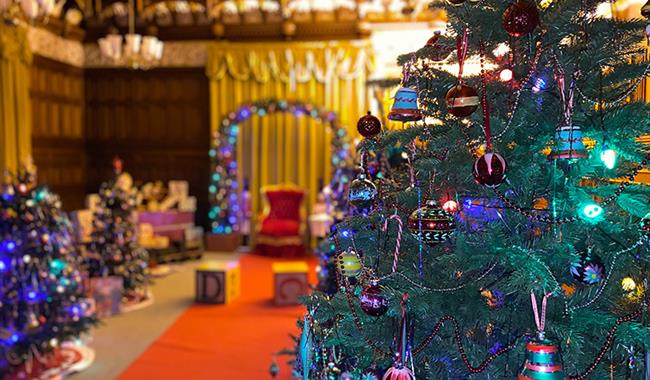 The ballroom at Bletchley Park decorated for Christmas with Christmas trees, toys, presents and a chair for Father Christmas
