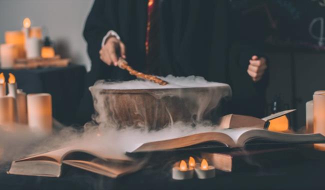 A child preparing a concoction with candles, books and fog in the background