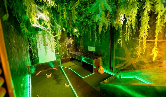 mini golf course, lit up by green lights