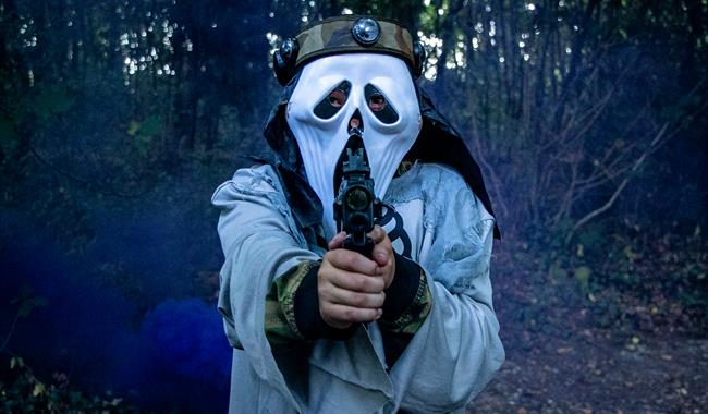 A person in a halloween mask, holding a laser tag gun