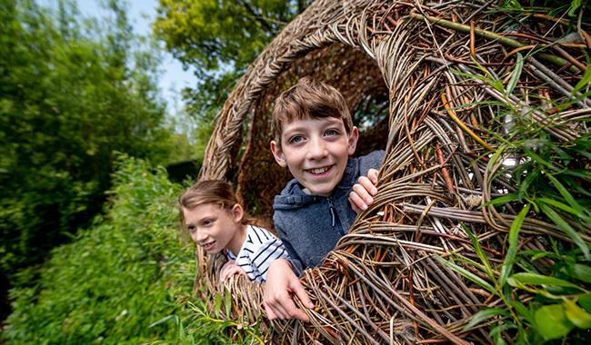 Children look out of a large woven willow sphere at Arundel Wetland Centre