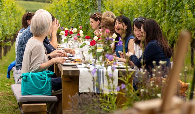 People sat around a table in the vineyard eating